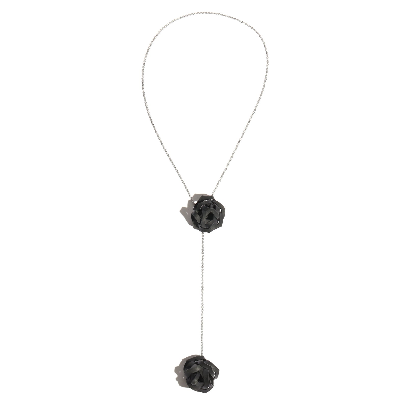 Black rose-shaped lariat necklace on a white background