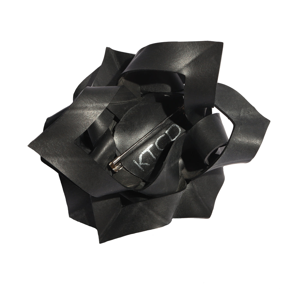 Black rubber flower-shaped brooch on white background