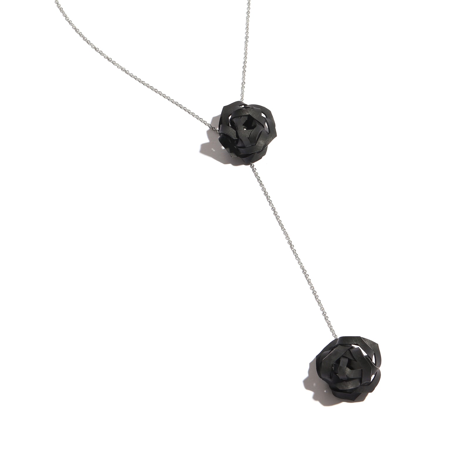 Black rose-shaped lariat necklace on a white background