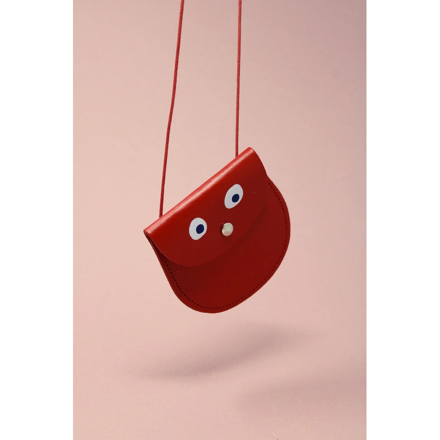 Red pouch with cartoonish face on a pink background