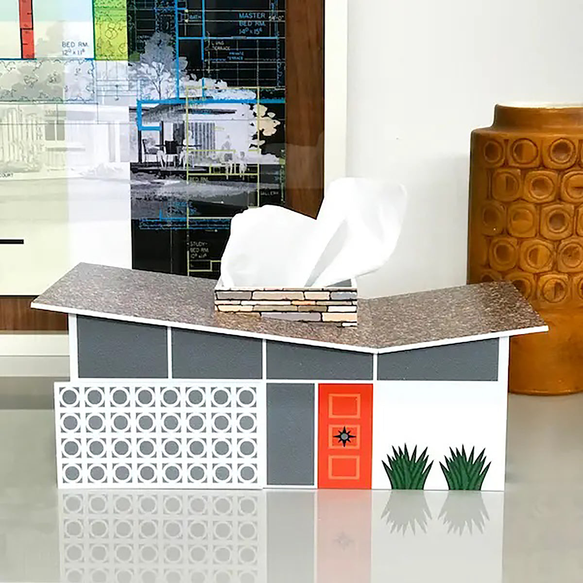 Mid-century modern home shaped tissue box on a desk with other decor