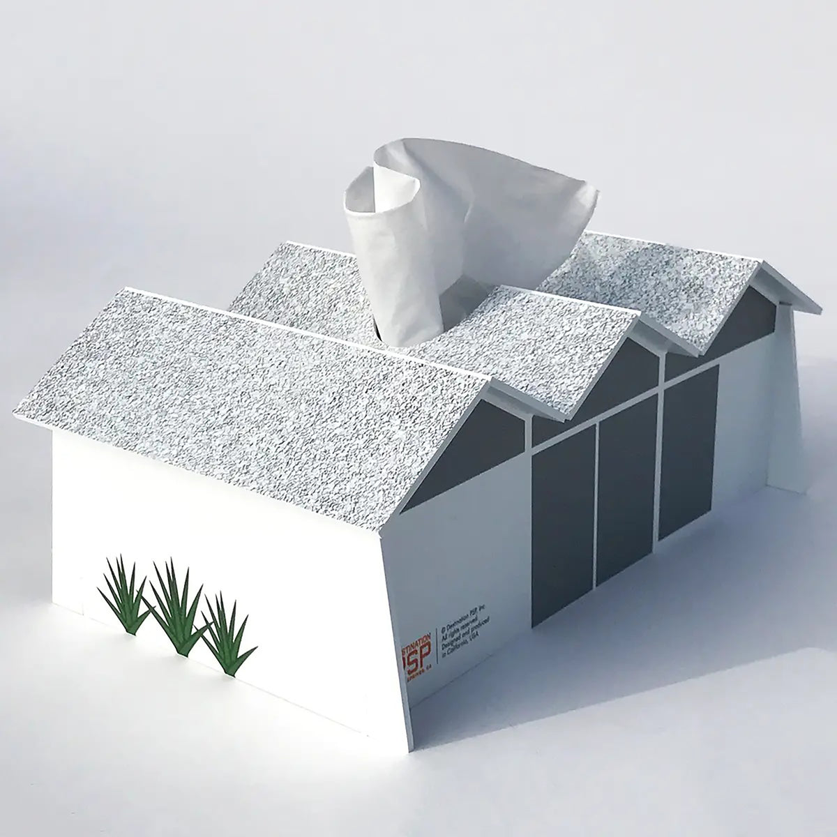 Tissue box shaped like a mid-century modern home with a textured roof and a cylindrical object on top against a light gray background.