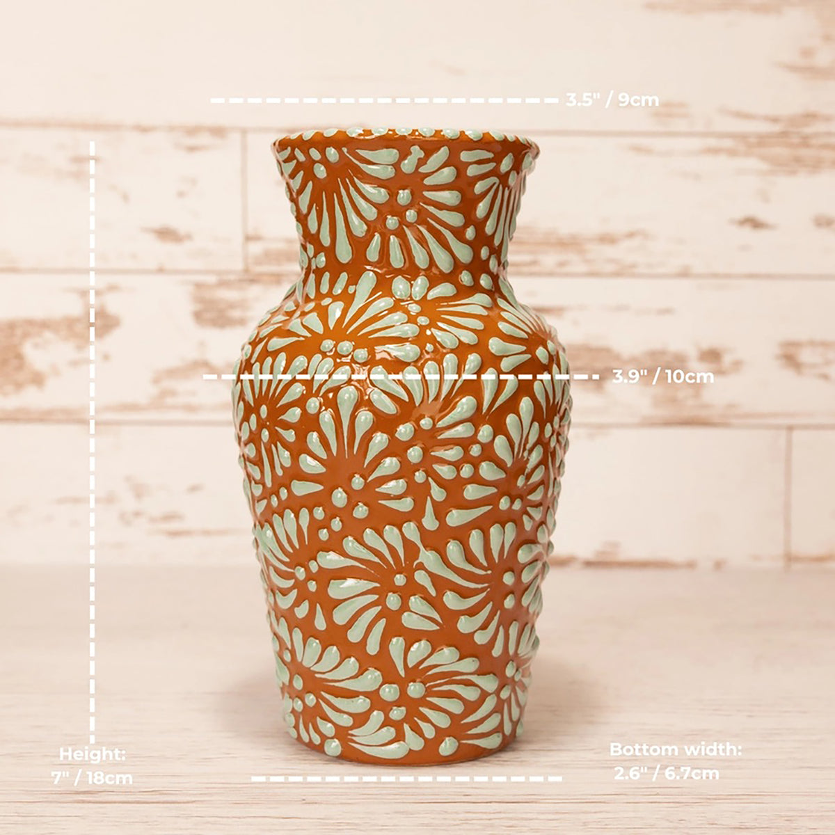 An orange ceramic vase with a white floral pattern, shown with dimension lines and text indicating its height, bottom width, and middle diameter.