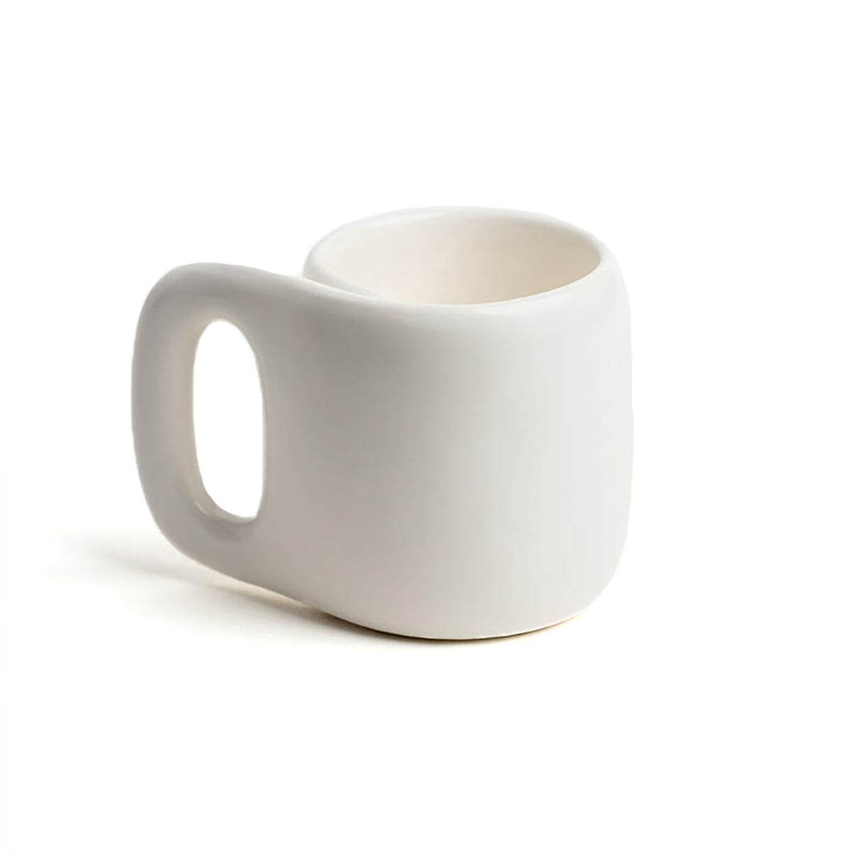 A minimalist white ceramic mug with a unique, rounded rectangular shape and a large integrated handle, shown on a clean white background.