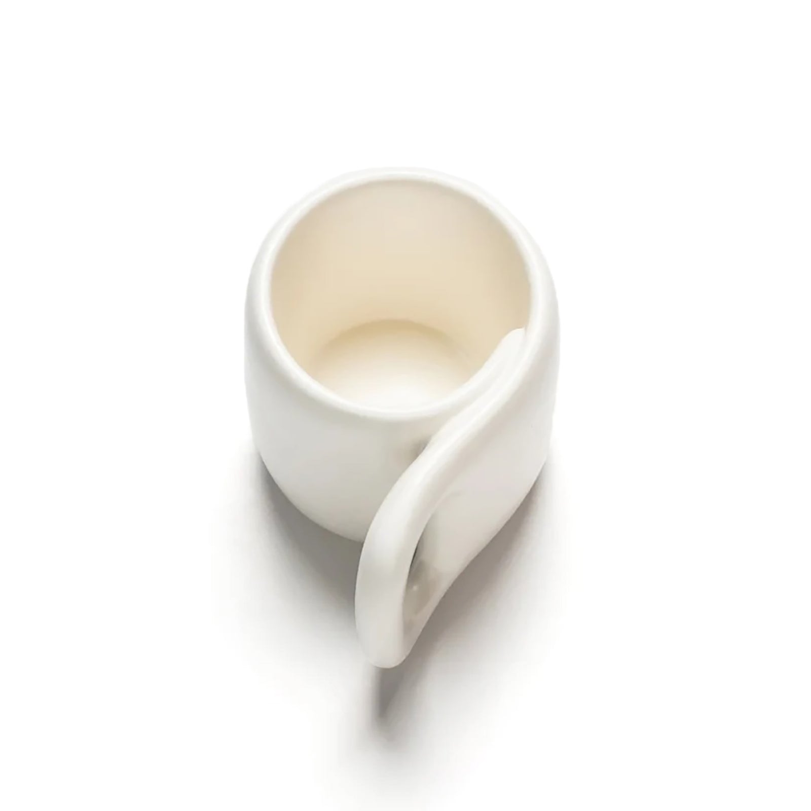 A minimalist white ceramic mug with a unique, rounded rectangular shape and a large integrated handle, shown on a clean white background.