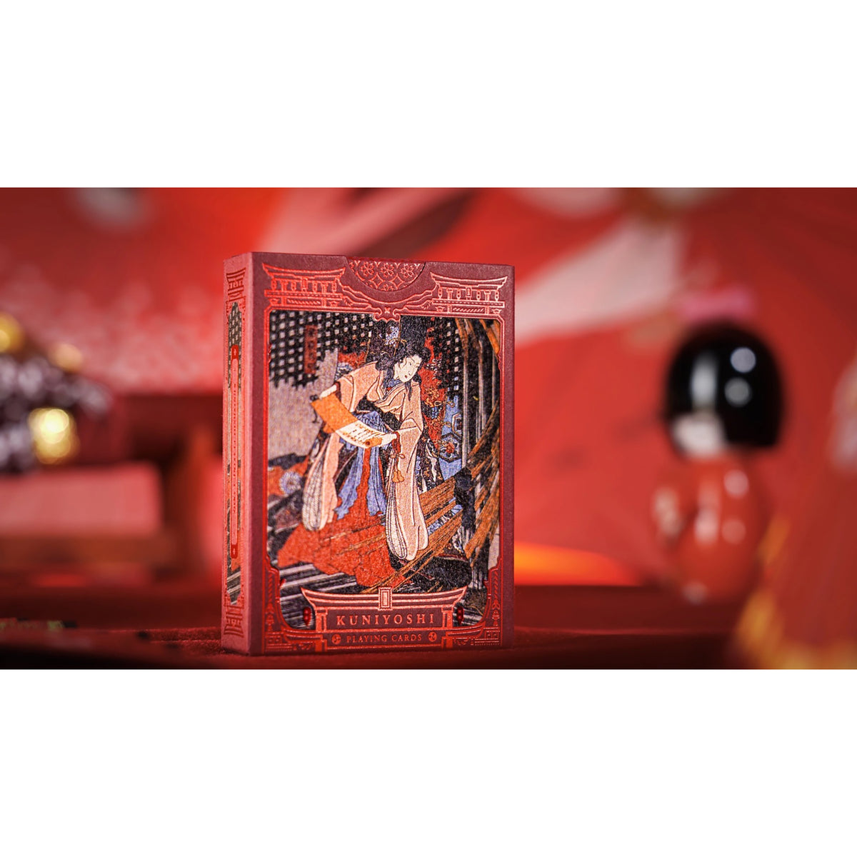 A red deck box for 'Kuniyoshi' card art, featuring a Japanese ukiyo-e woodblock illustration of a samurai warrior, set against a blurred red background.