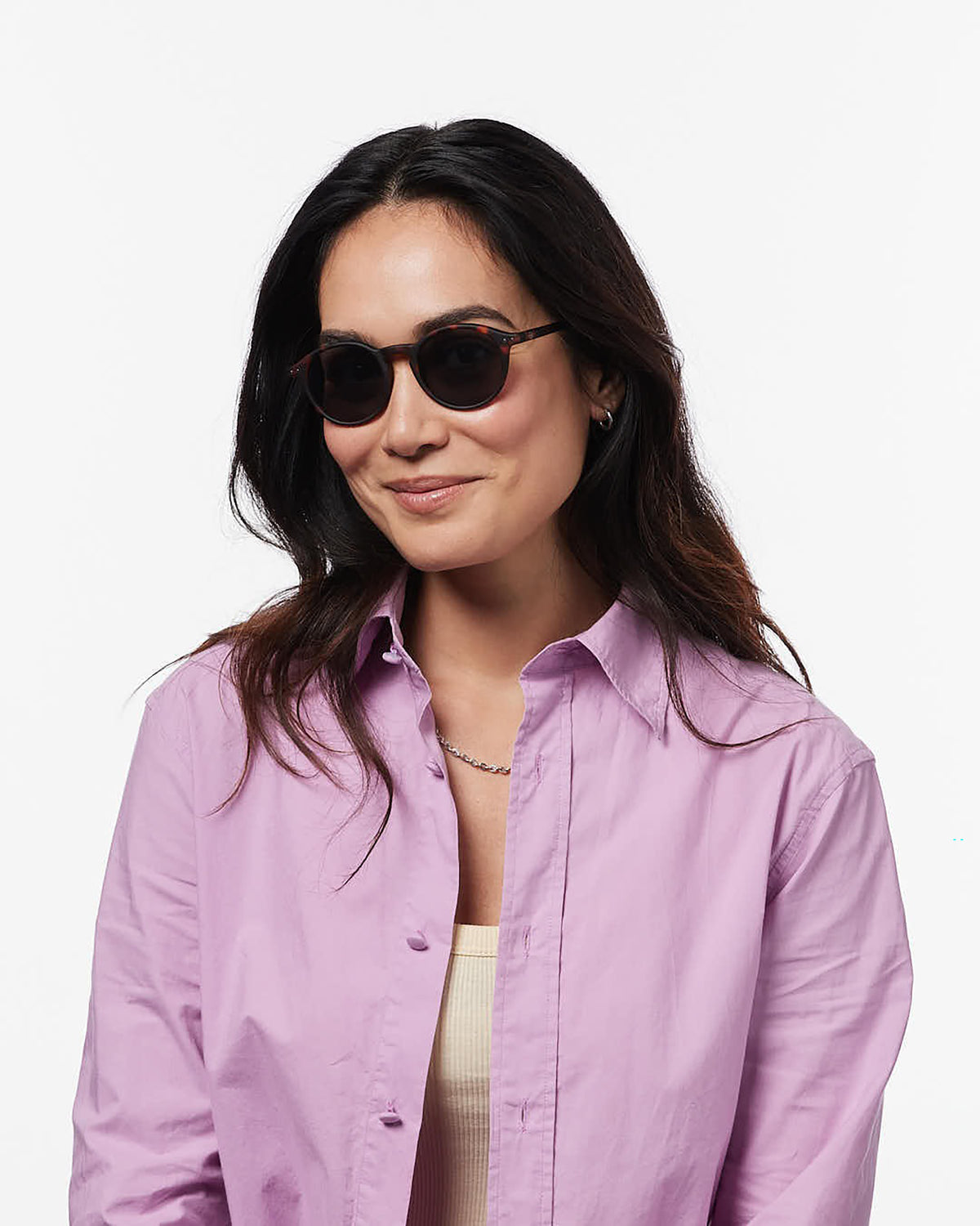 Woman wearing a purple shirt and sunglasses on a white background