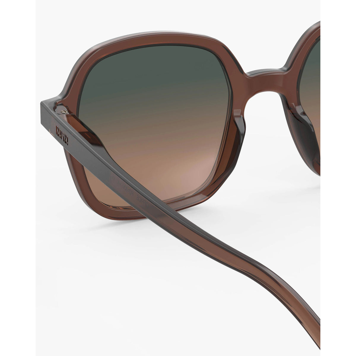 Close-up of a pair of sunglasses with a translucent brown acetate frame and gradient brown-to-black lenses, showing the side temple with the brand name 'DKNY' printed in white.