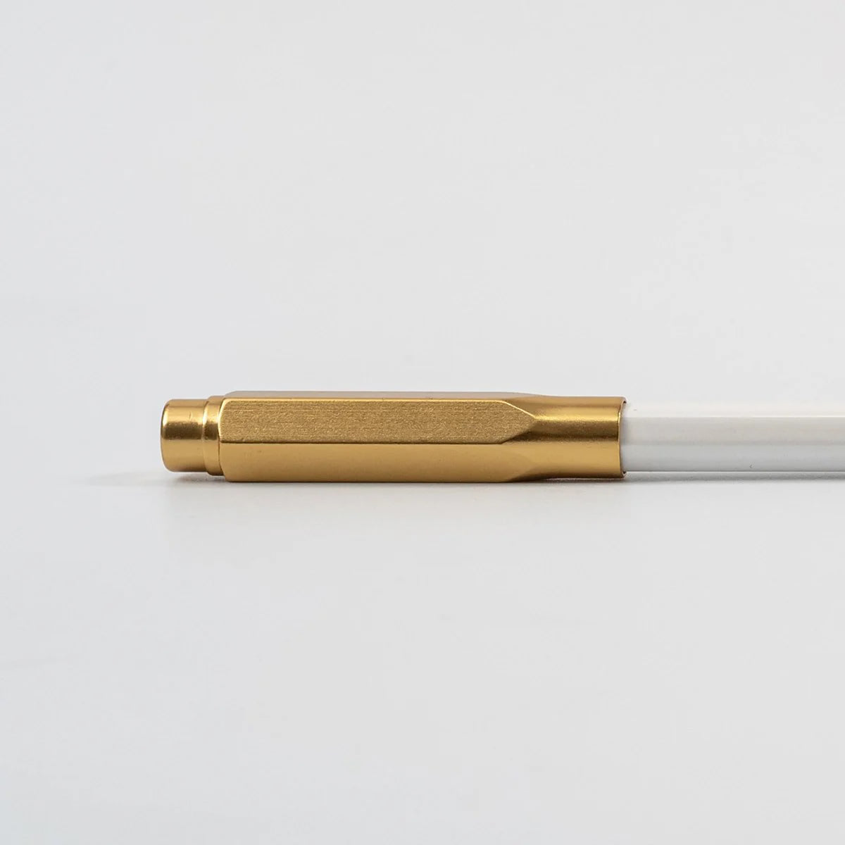 Pen with gold cap and white body on a light gray background