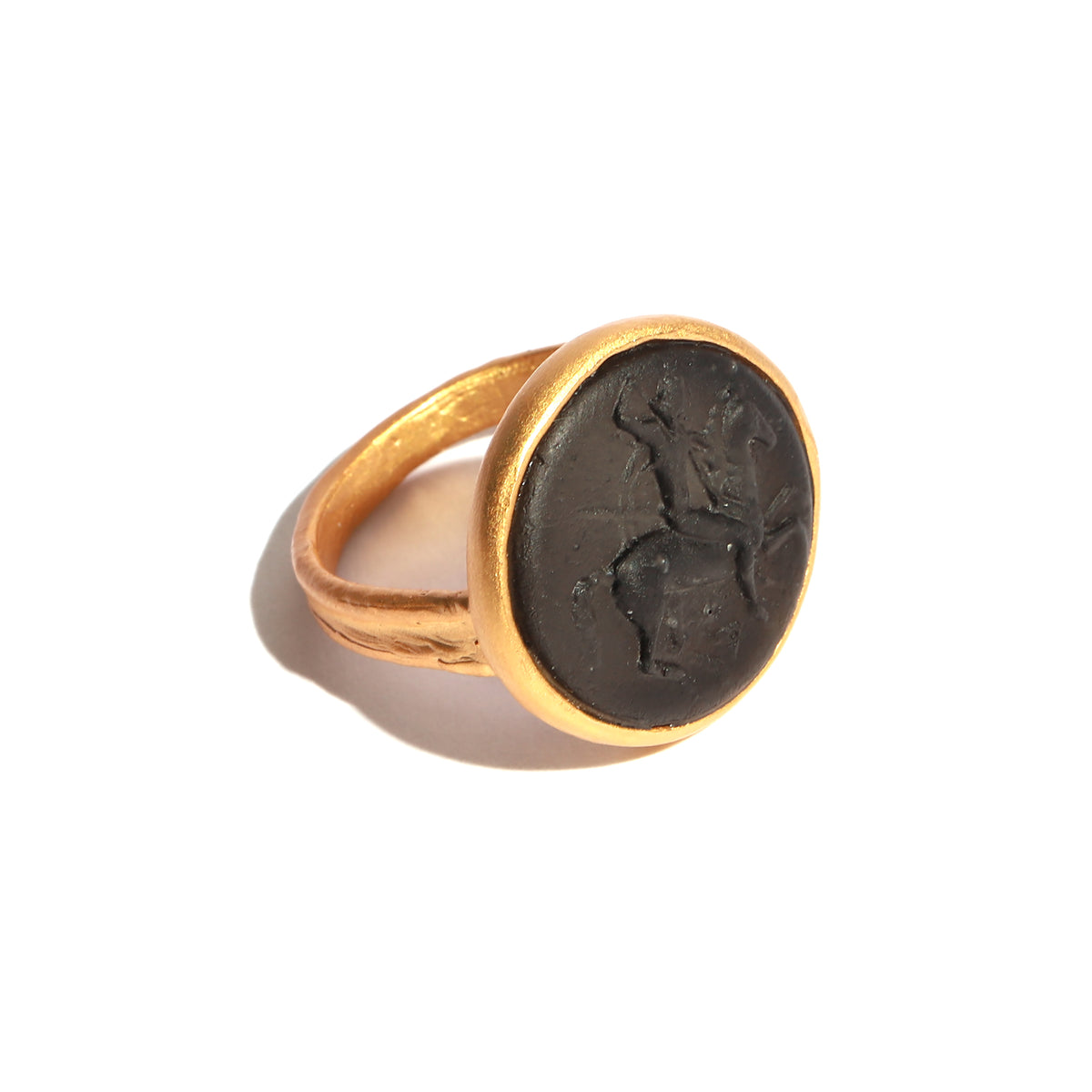 Gold ring with a black stone featuring an engraved design on a white background