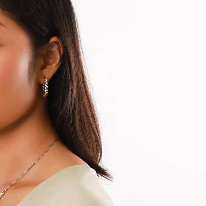 Silver hoop earrings with twisted design on a white background
