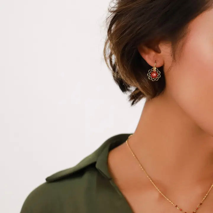 Gold earrings with red floral design on a white background