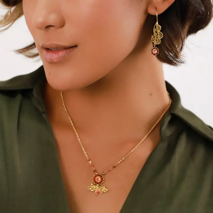 Close-up of a woman wearing a gold necklace and earrings with a white background