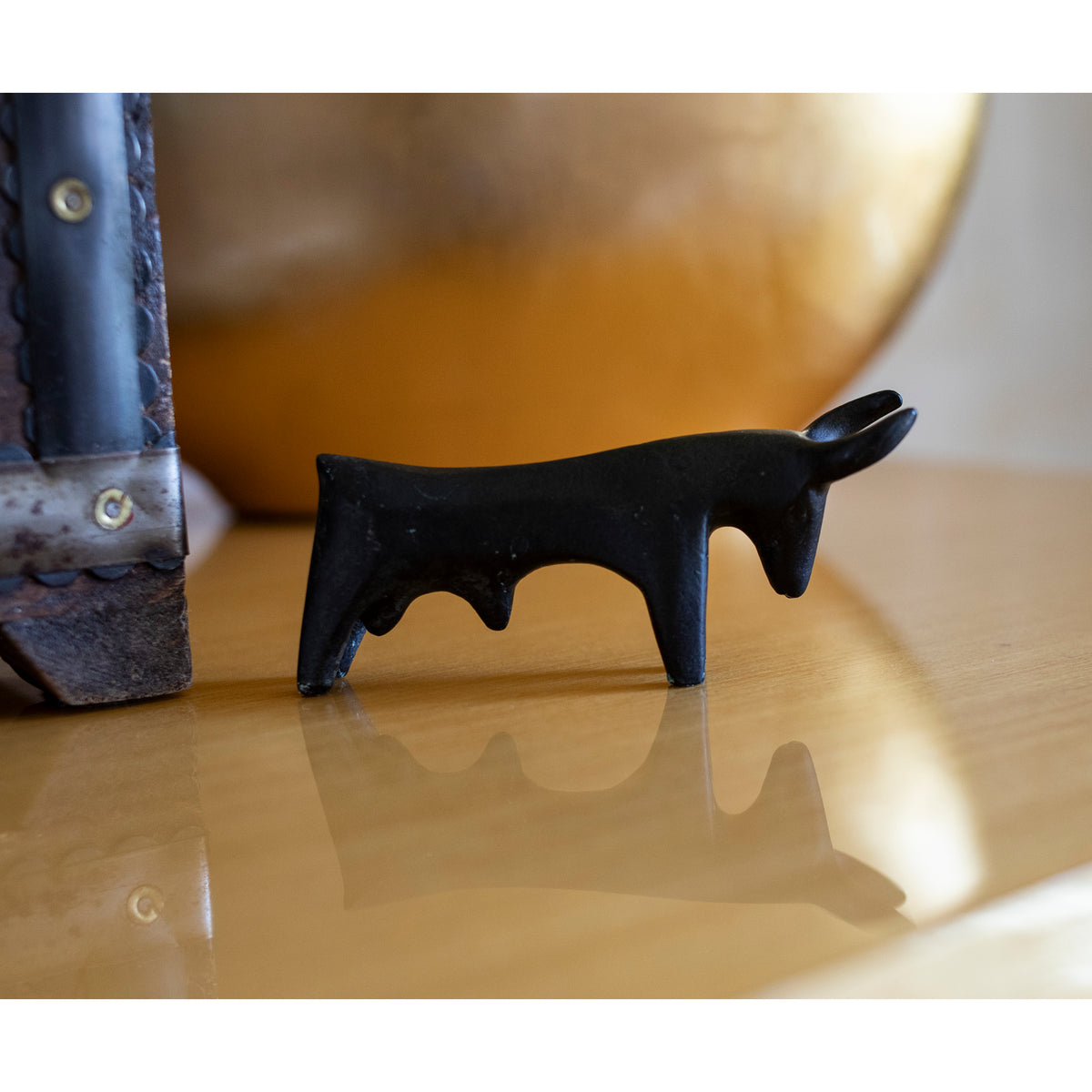 Black bull figurine on a reflective surface with a blurred background