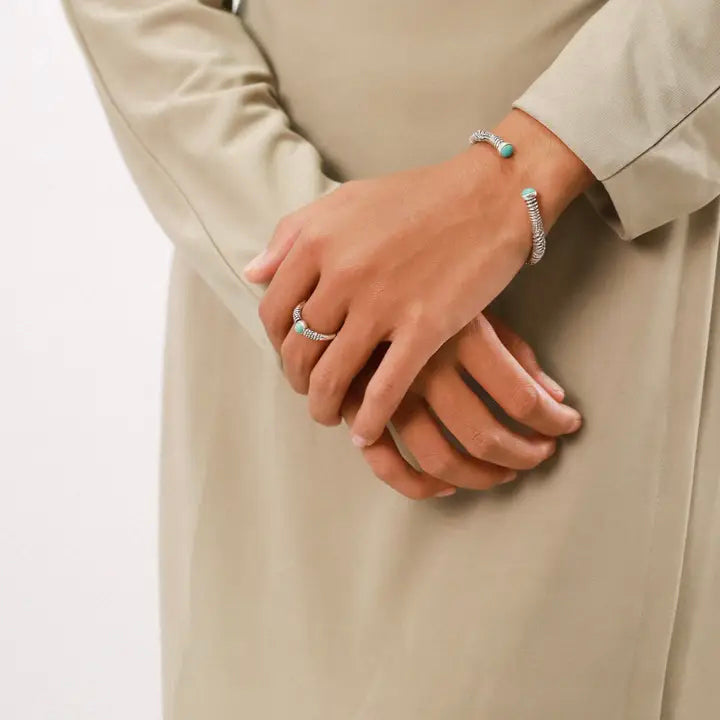 Close-up of hands wearing rings and bracelets on a neutral background