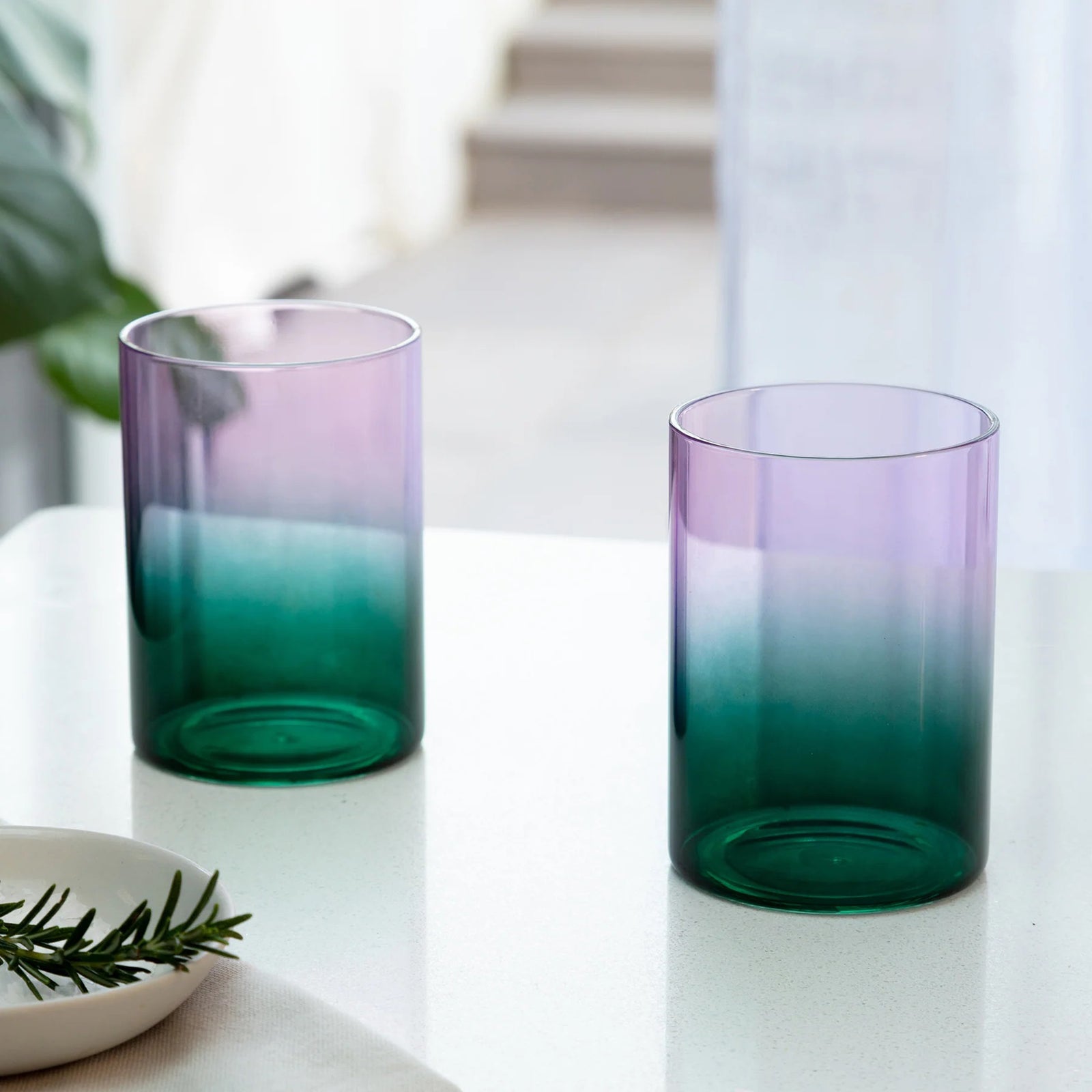 Gradient glass tumbler transitioning from purple to green on a white background