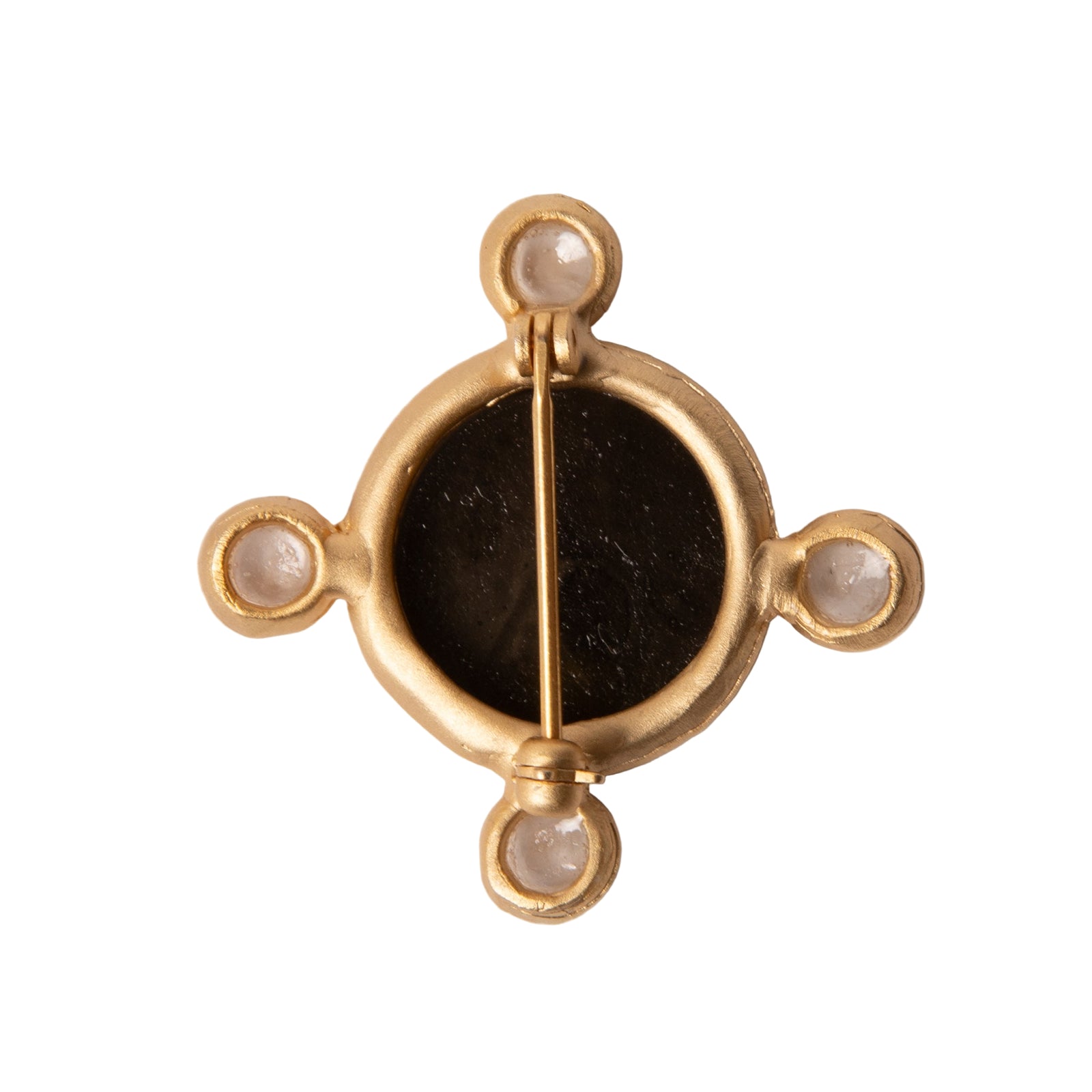 Gold jewelry piece with a dark central stone on a light gray background