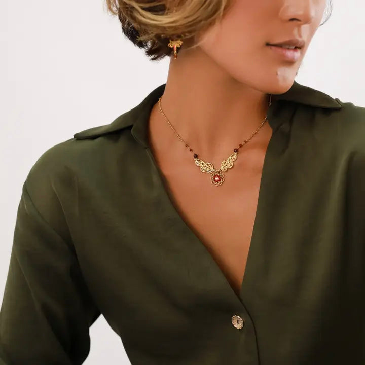 Woman wearing a green blouse with a necklace on a plain background
