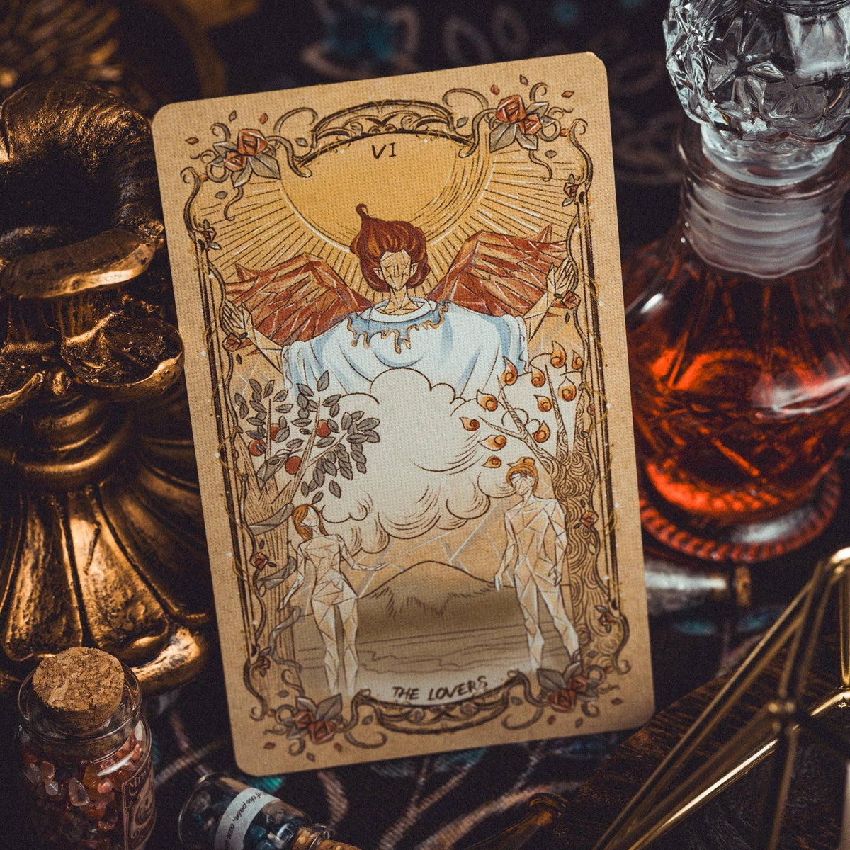 Tarot card titled 'The Lover' with decorative objects on a dark surface