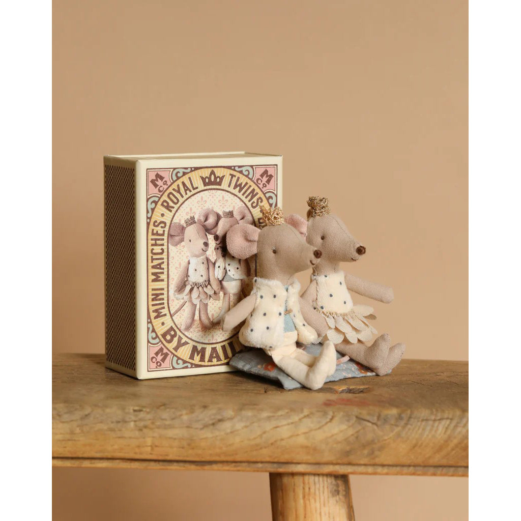 Two small mouse figurines with a decorative box on a wooden surface