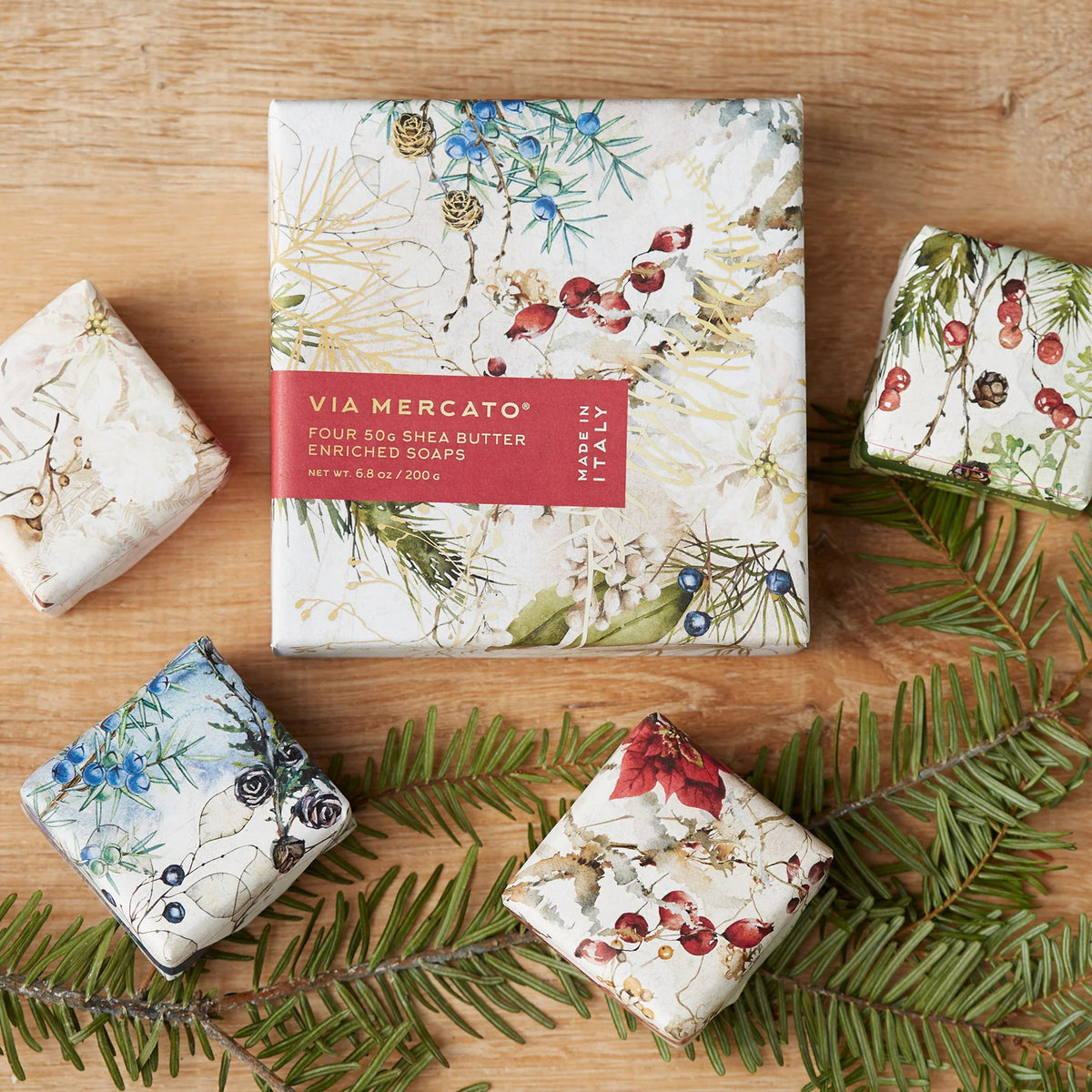 Floral-patterned soap bars and packaging on a wooden surface with greenery.