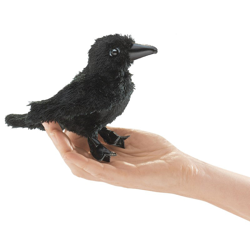 Black plush raven on a hand against a white background