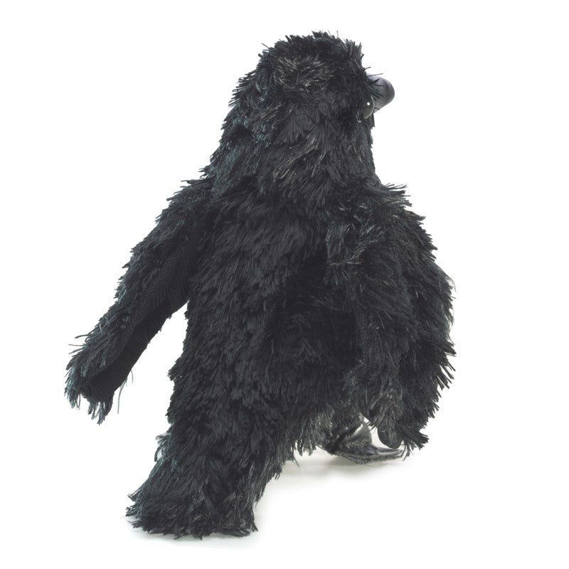 Black plush raven standing on a white background facing away