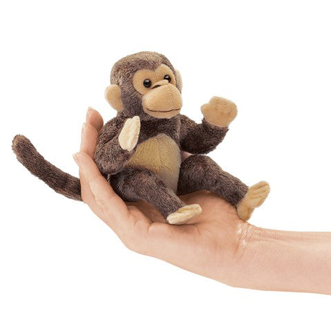 Small plush monkey toy held in a hand against a white background