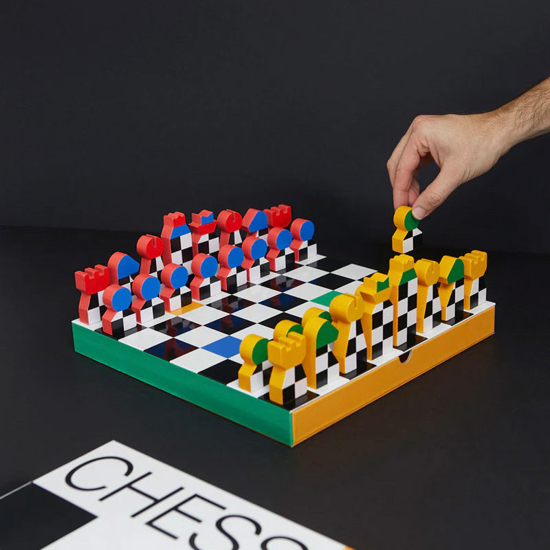 Colorful chess set with a hand placing a piece on a black background