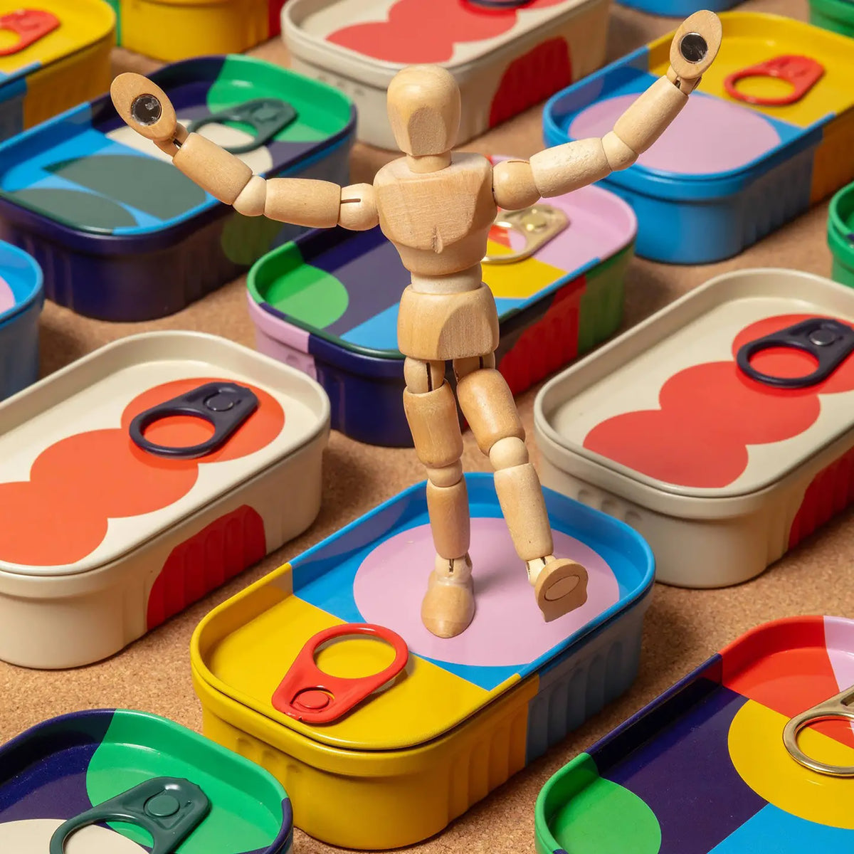 Wooden mannequin among colorful containers with various shapes and colors