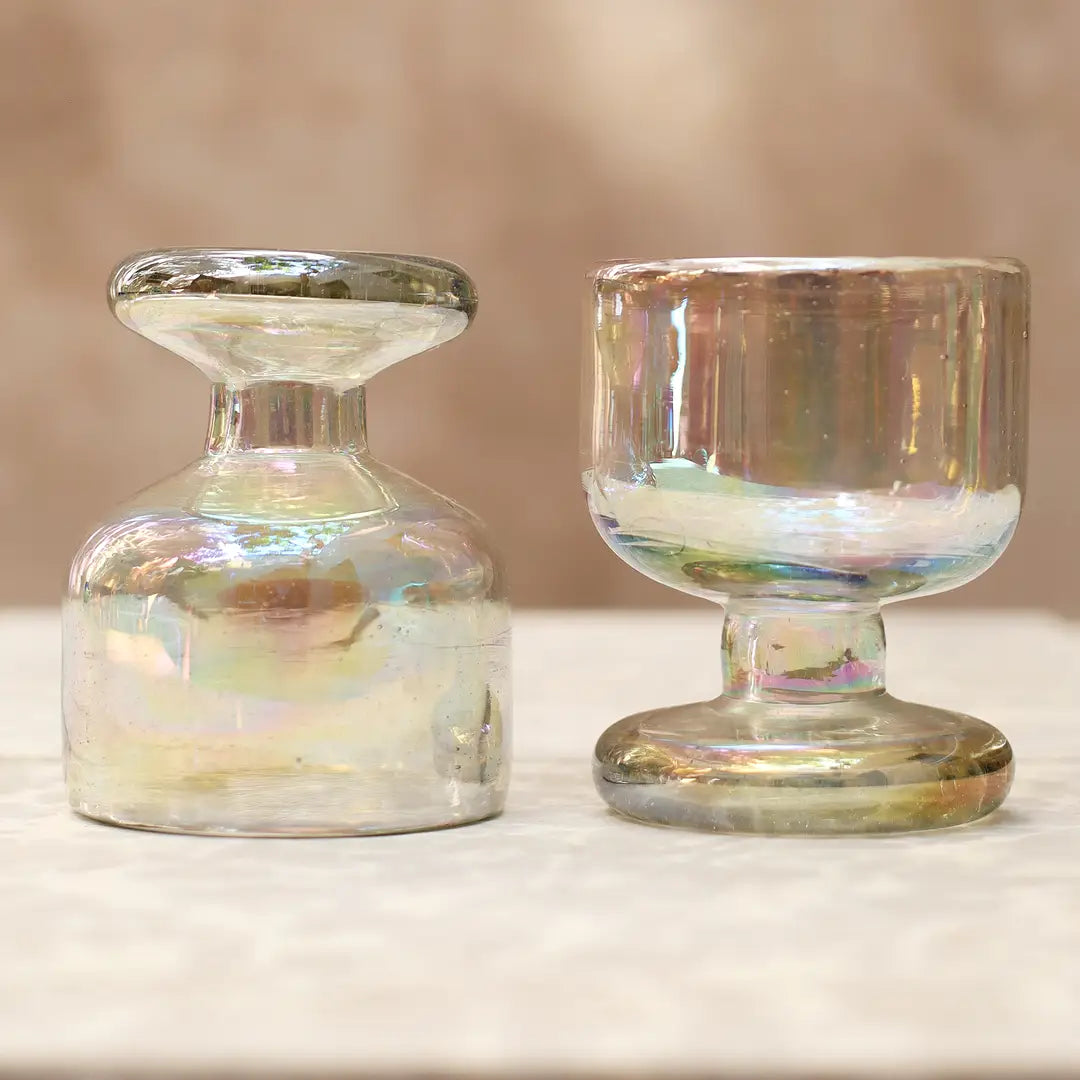 Two iridescent glass candle holders on a neutral background