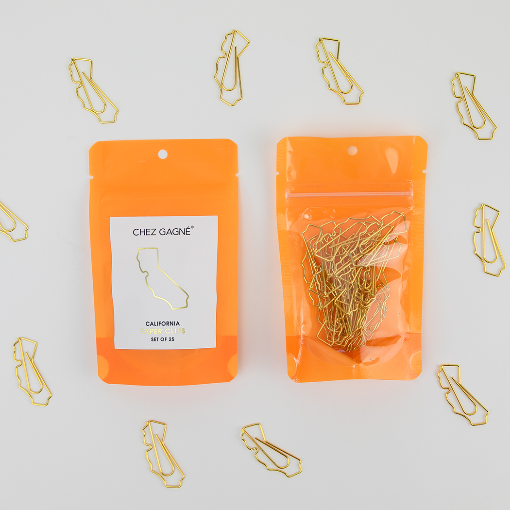 Two orange packages of gold paper clips with 'Chez Gagne' branding on a light gray background.