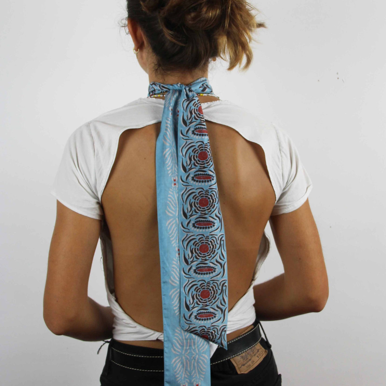 A blue silk headband with red patterned designs, displayed against a white background.