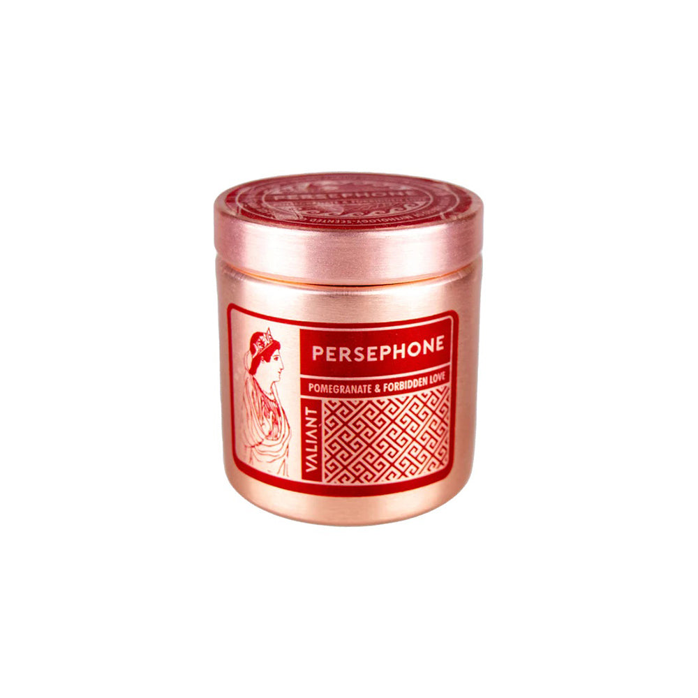 A bronze-colored candle vessel labeled 'PERSEPHONE' with an image of a woman scented with Pomegranate & Forbidden Love