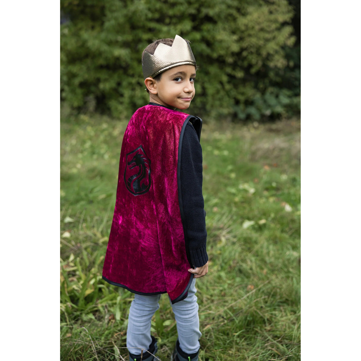Child wearing a red cape and crown outdoors