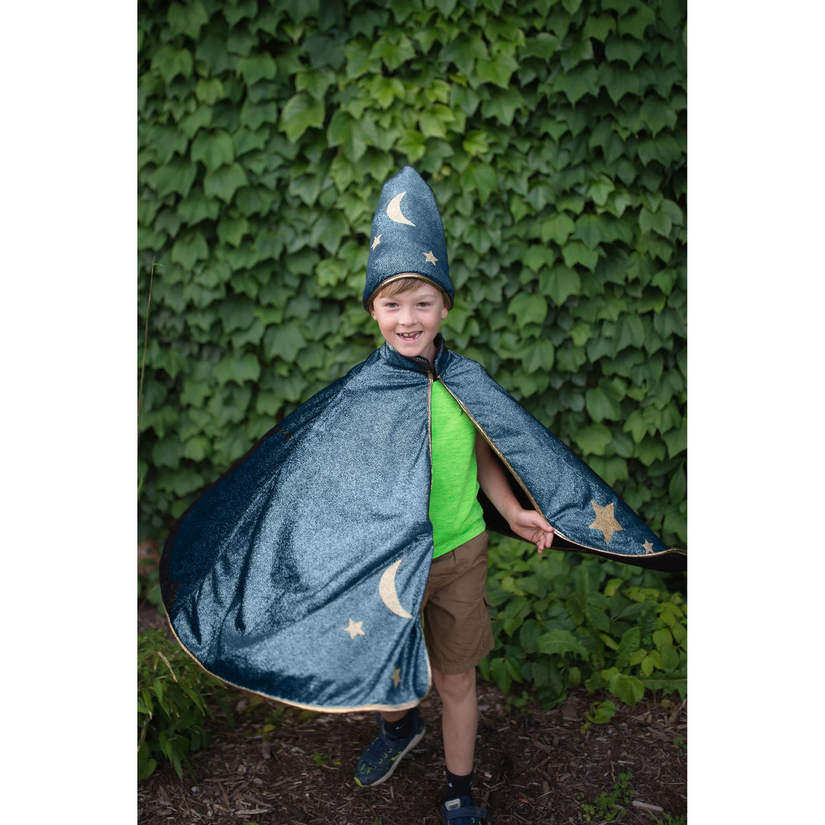 Child wearing a blue wizard costume with stars and moons against a green ivy background
