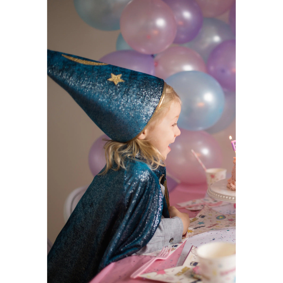 Child in a blue wizard costume with balloons in the background