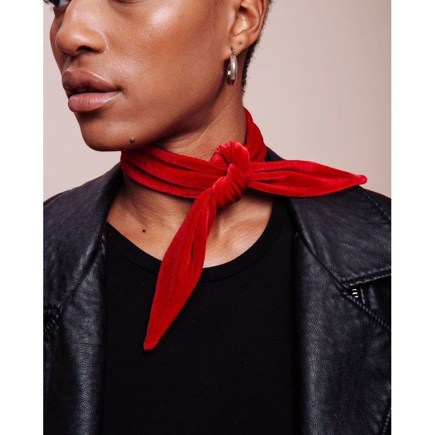 Person wearing a red neckerchief and black leather jacket on a beige background