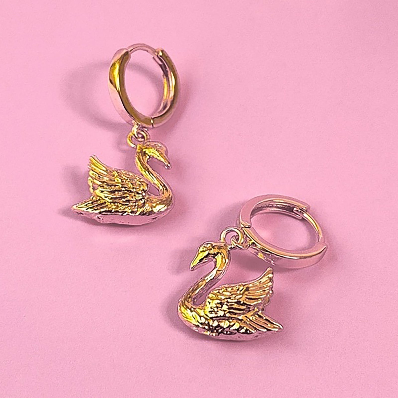 Gold and silver swan-shaped earrings on a white background