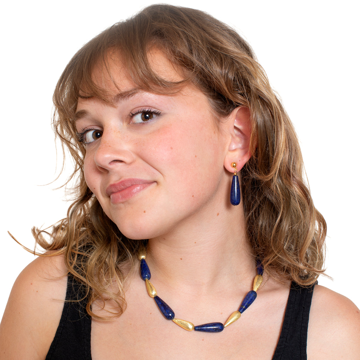 Woman wearing a blue and gold necklace and earrings on a white background