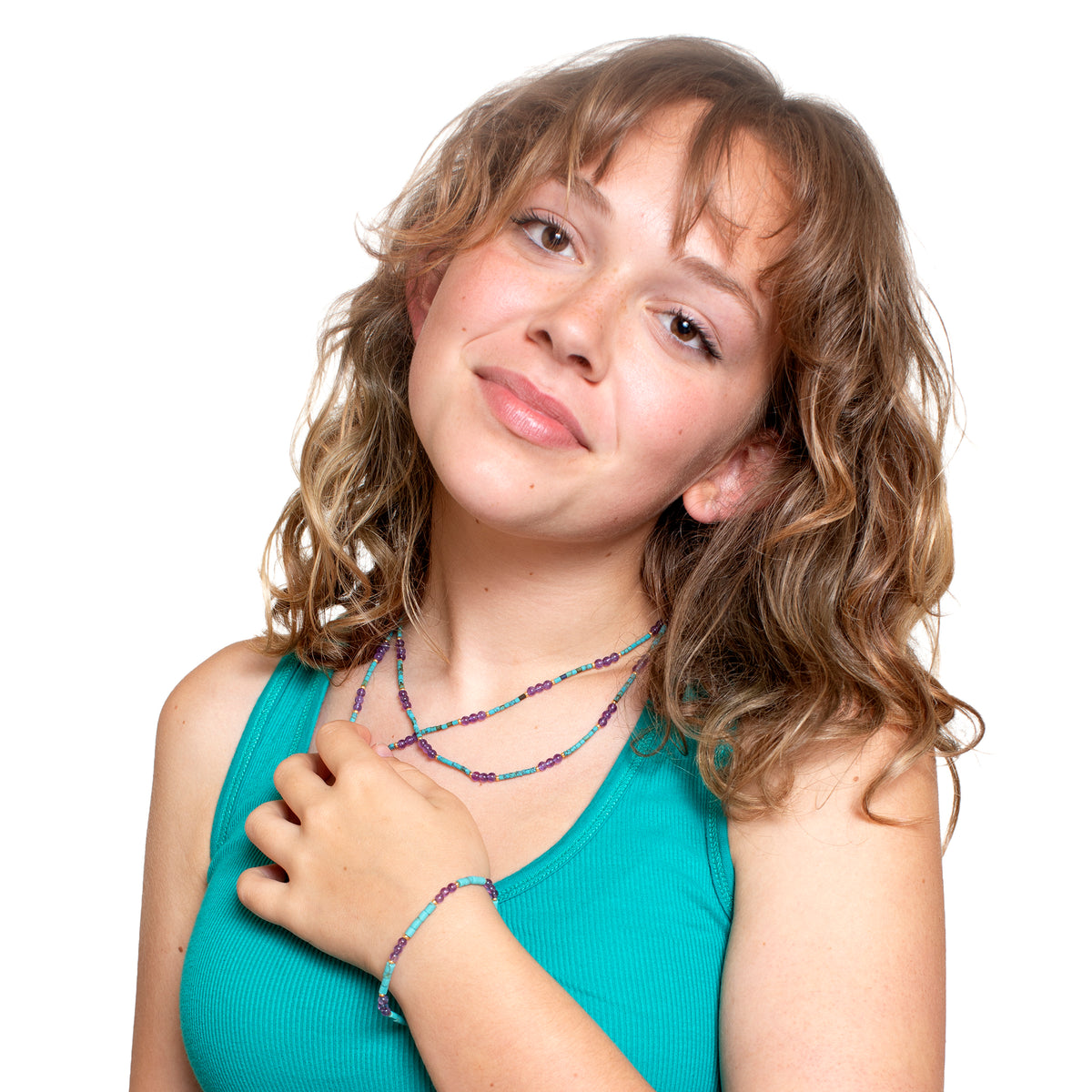 Young girl wearing a turquoise top with colorful jewelry on a white background