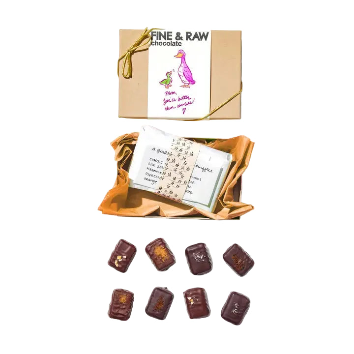 Box of fine and raw chocolate with a card and chocolate pieces on a white background