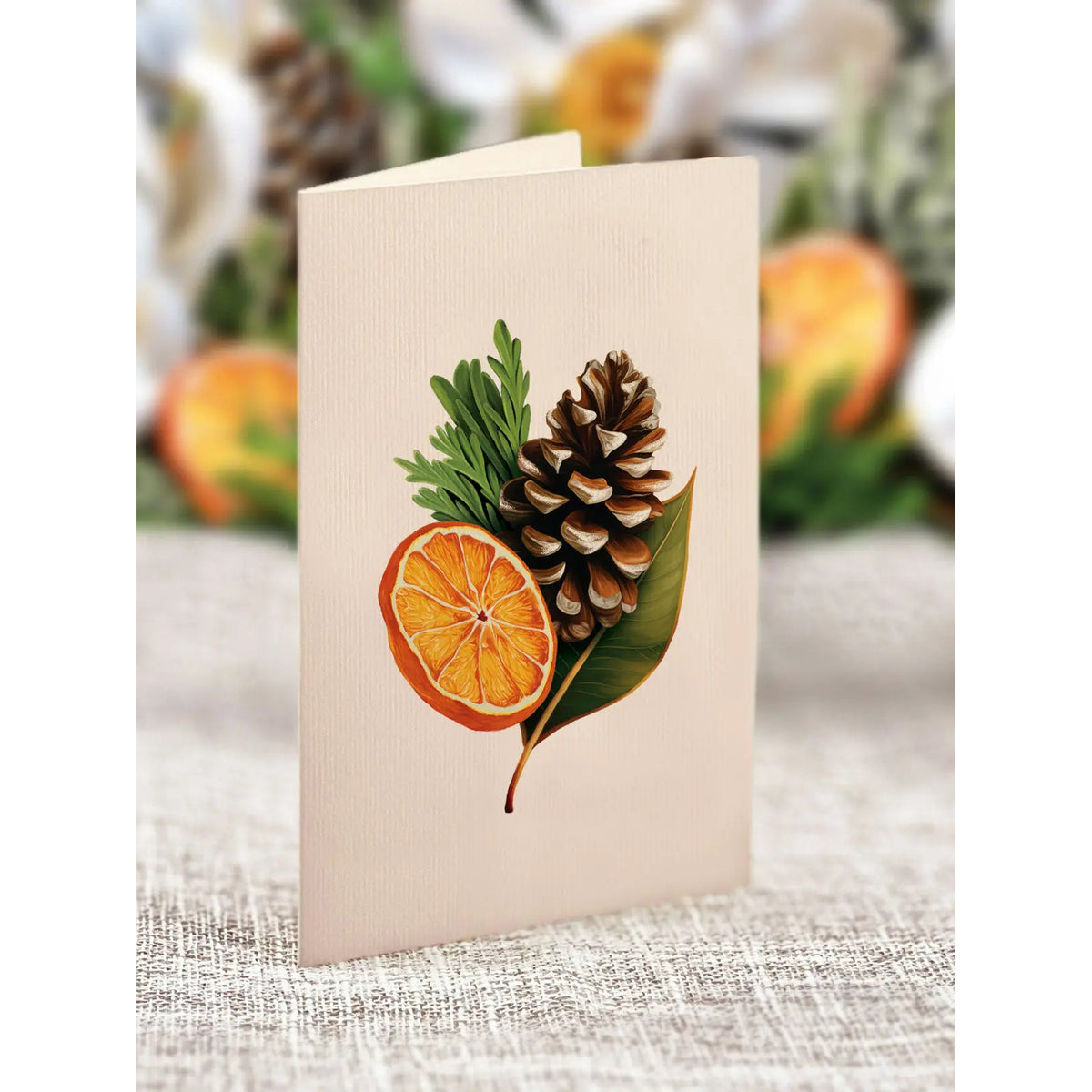 Greeting card with autumn design featuring an orange, pine cone, and leaf on a textured surface.
