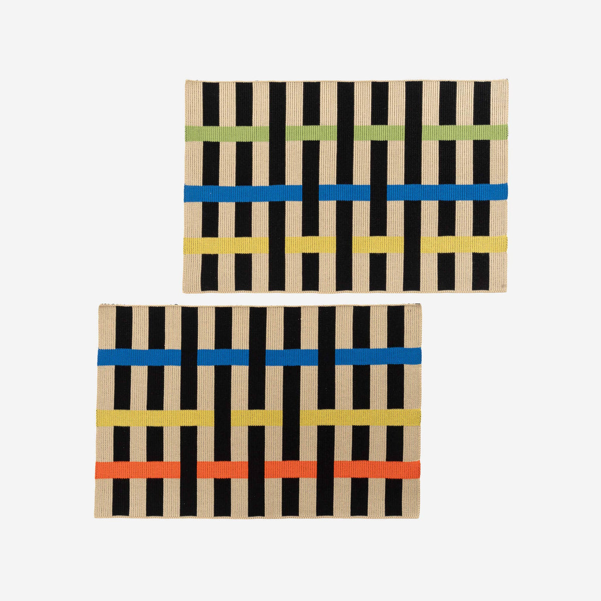 Two rectangular woven placemats with a black and beige vertical stripe pattern and colorful horizontal bands, displayed on a light gray background.