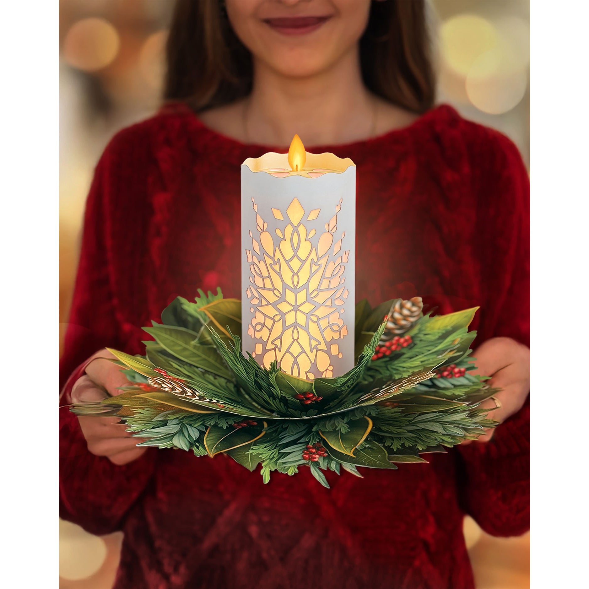 Light-up holiday candle with decorative packaging featuring greenery and pinecones.