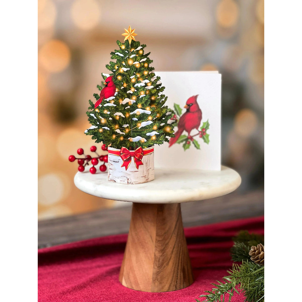 Decorative Christmas tree with lights and red cardinal birds on a small table.