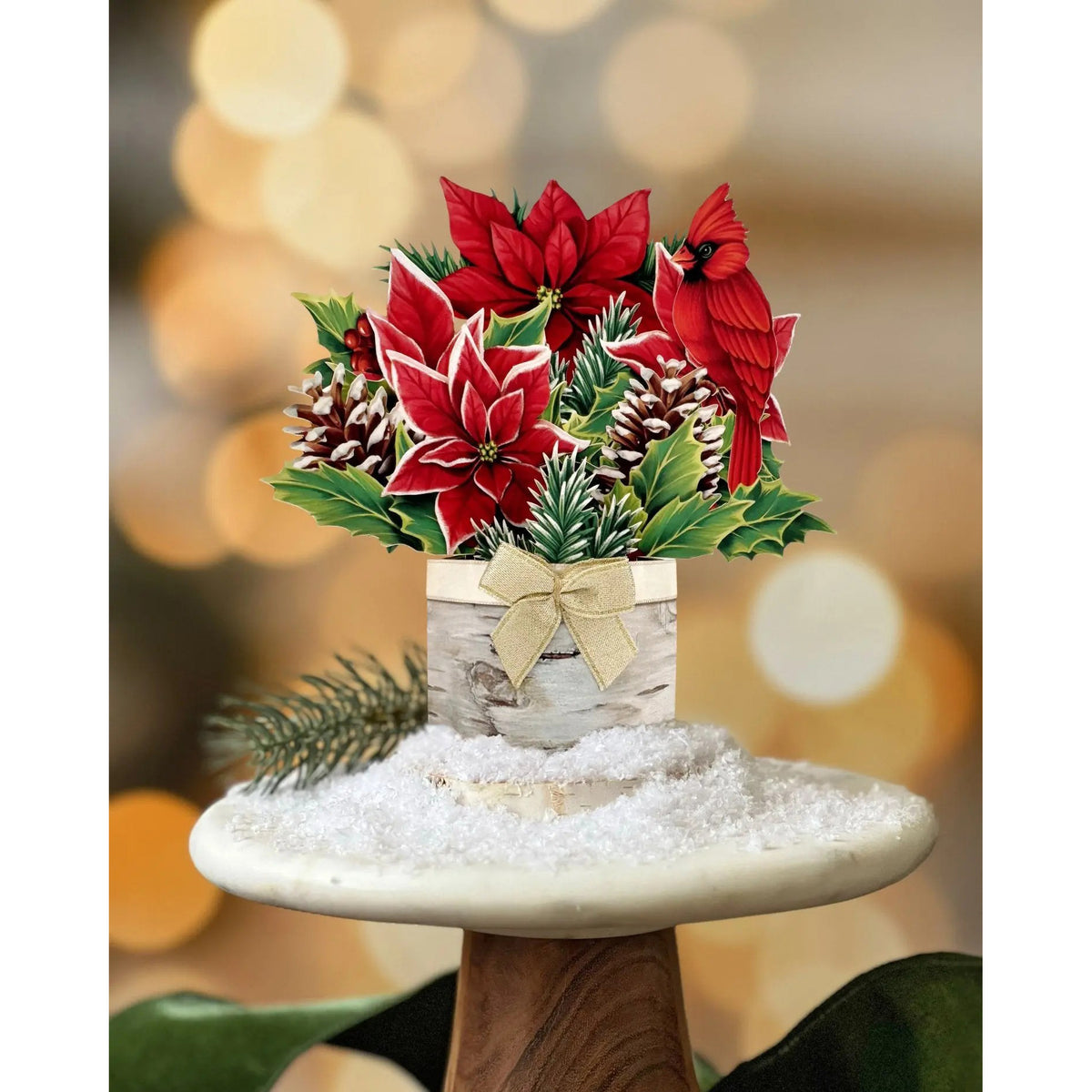 Decorative Christmas arrangement with poinsettias, pinecones, and a bow on a blurred bokeh background.