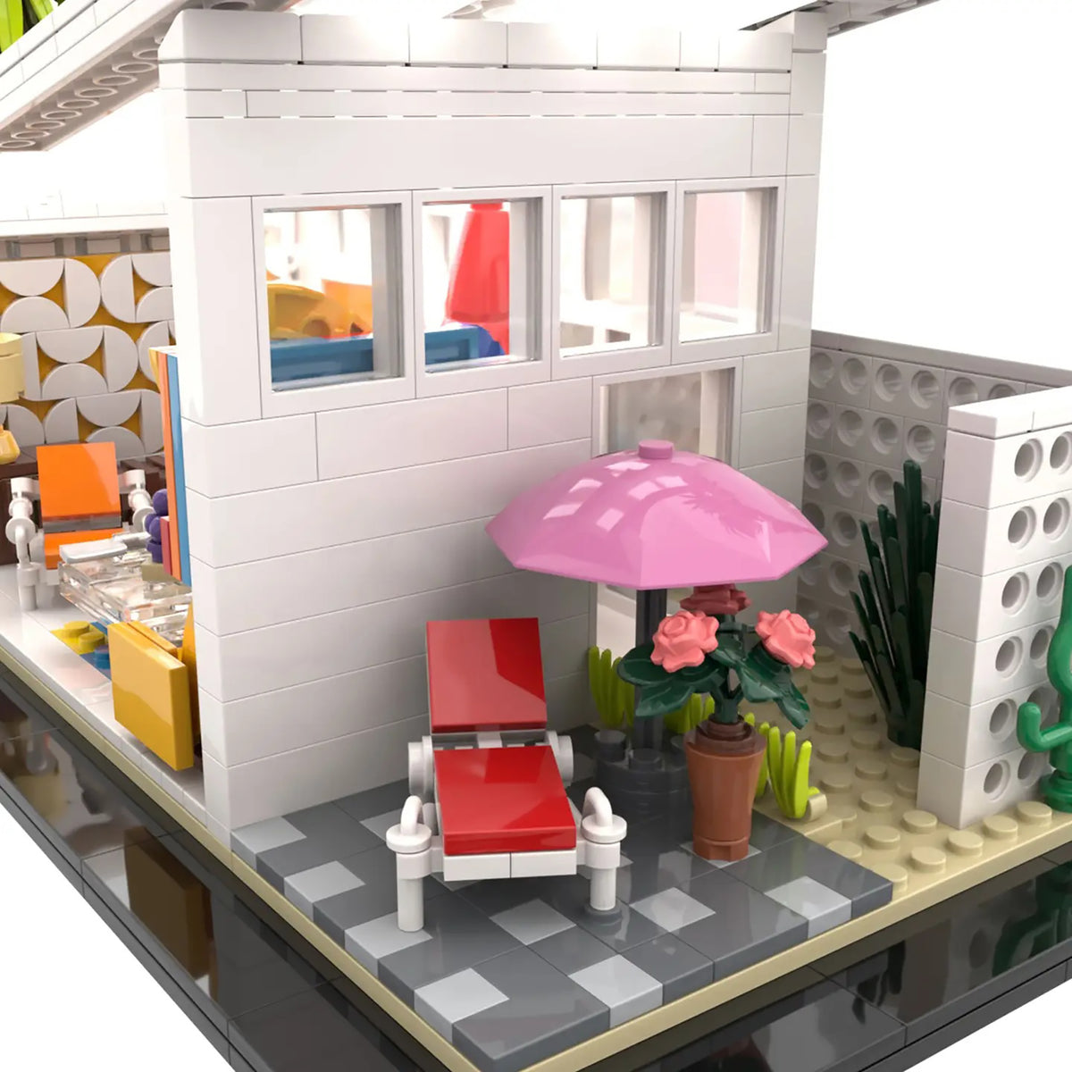 A detailed model of a modern house built from interlocking toy bricks, featuring a white exterior, a gray tiled patio, a pink umbrella, a red lounge chair, and a potted plant.