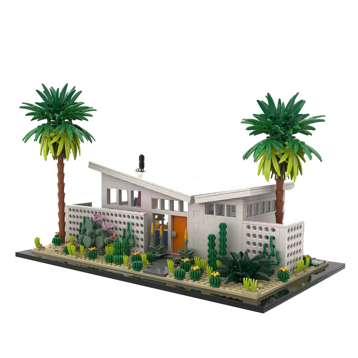 A detailed model of a mid-century modern house built from interlocking blocks, featuring two palm trees, cacti, and a landscaped garden on a white background.
