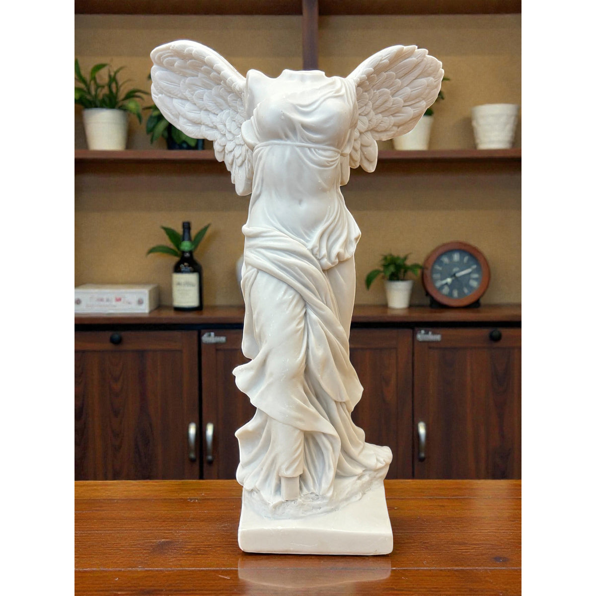 White statue of a winged figure on a wooden surface with a blurred background